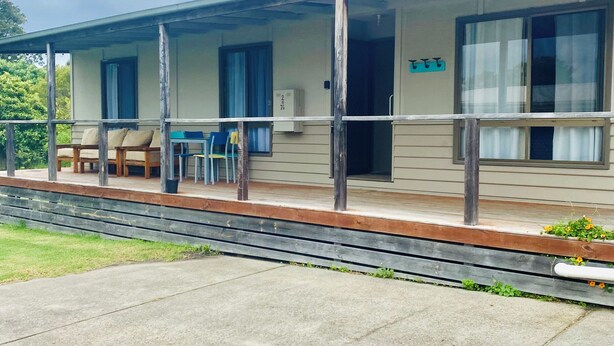 Ein Motel mit überdachter Veranda, Sitzgelegenheiten im Freien und einem kleinen Garten.