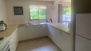 Eine Küche mit weißen Schränken, einer Spüle, einem Herd und einem Kühlschrank.