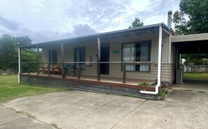 A single-story motel with a covered porch, a small outdoor seating area, and a visible garage door. - Peaceful holidays for family and pets. Visit pristine wilderness and beaches. (Mallacoota)