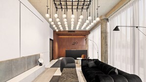 Eine moderne Lobby mit einer schwarzen Couch, einer Holz-Akzentwand und einer Pendelleuchte.