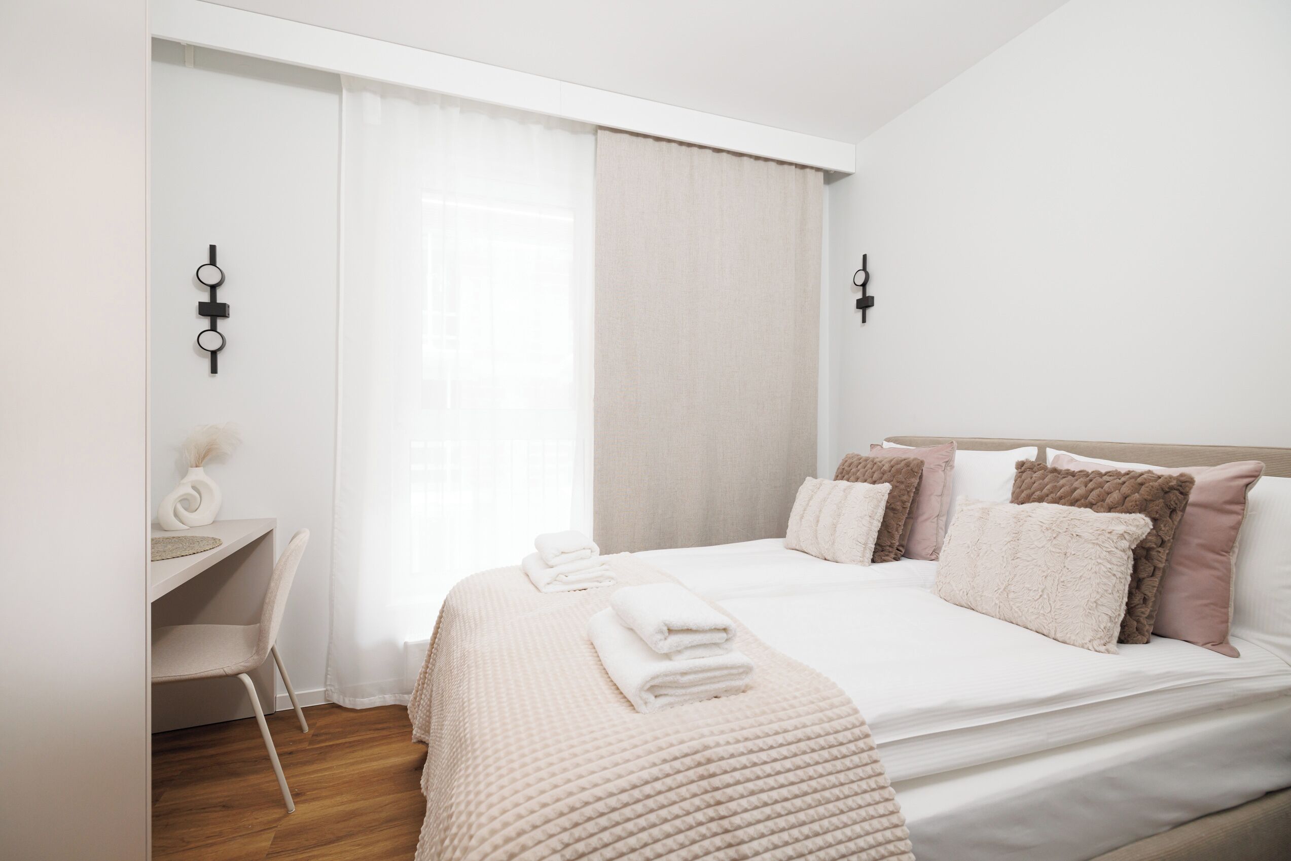 A modern bedroom with a bed, bedside tables, and a desk.
