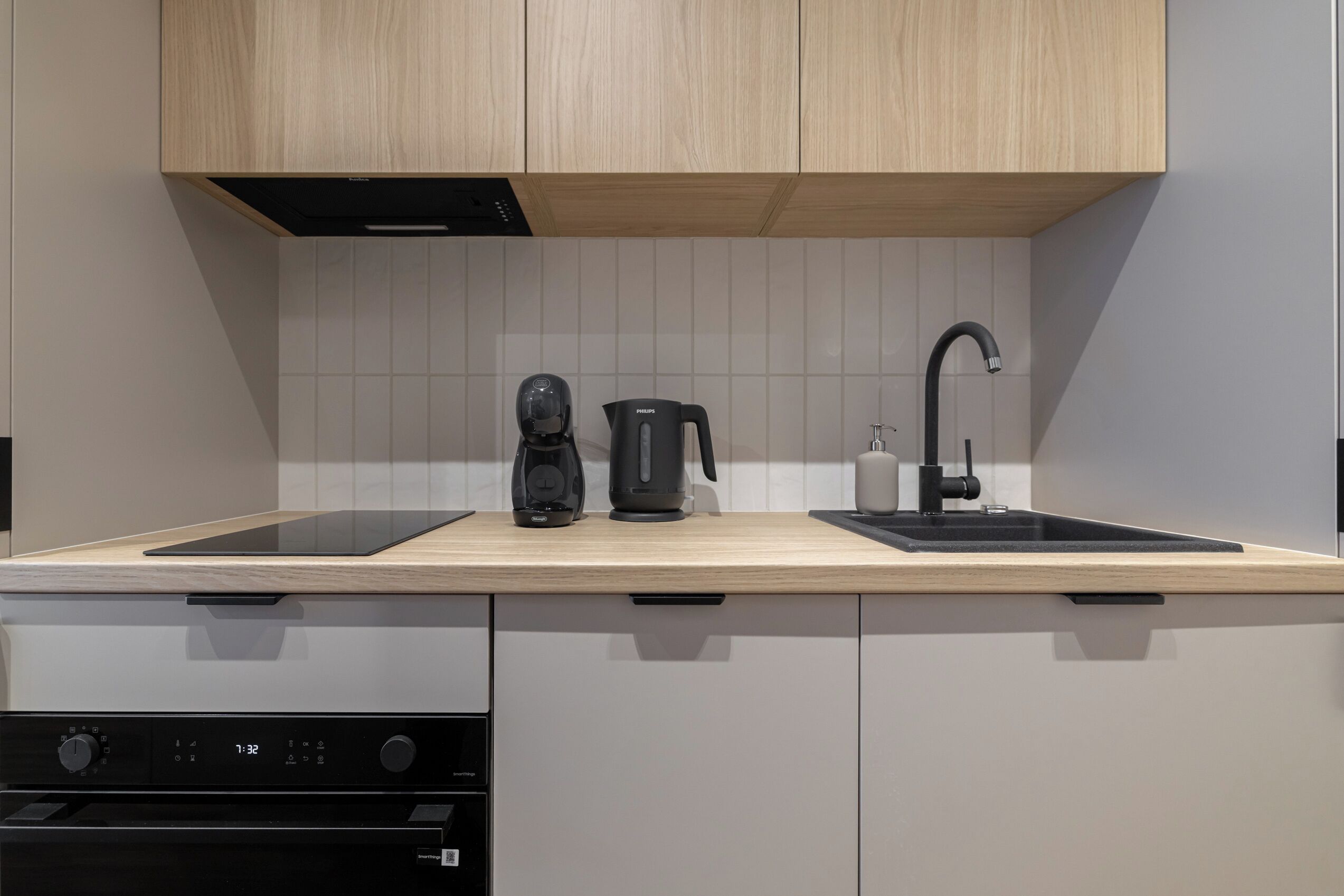 Una cocina moderna con encimera de madera, cafetera, hervidor y un lavabo.
