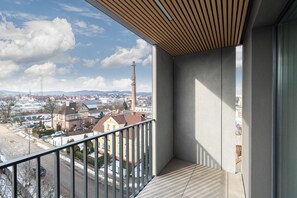Een balkon met uitzicht op een stadsgezicht, inclusief een kerktoren en woongebouwen.