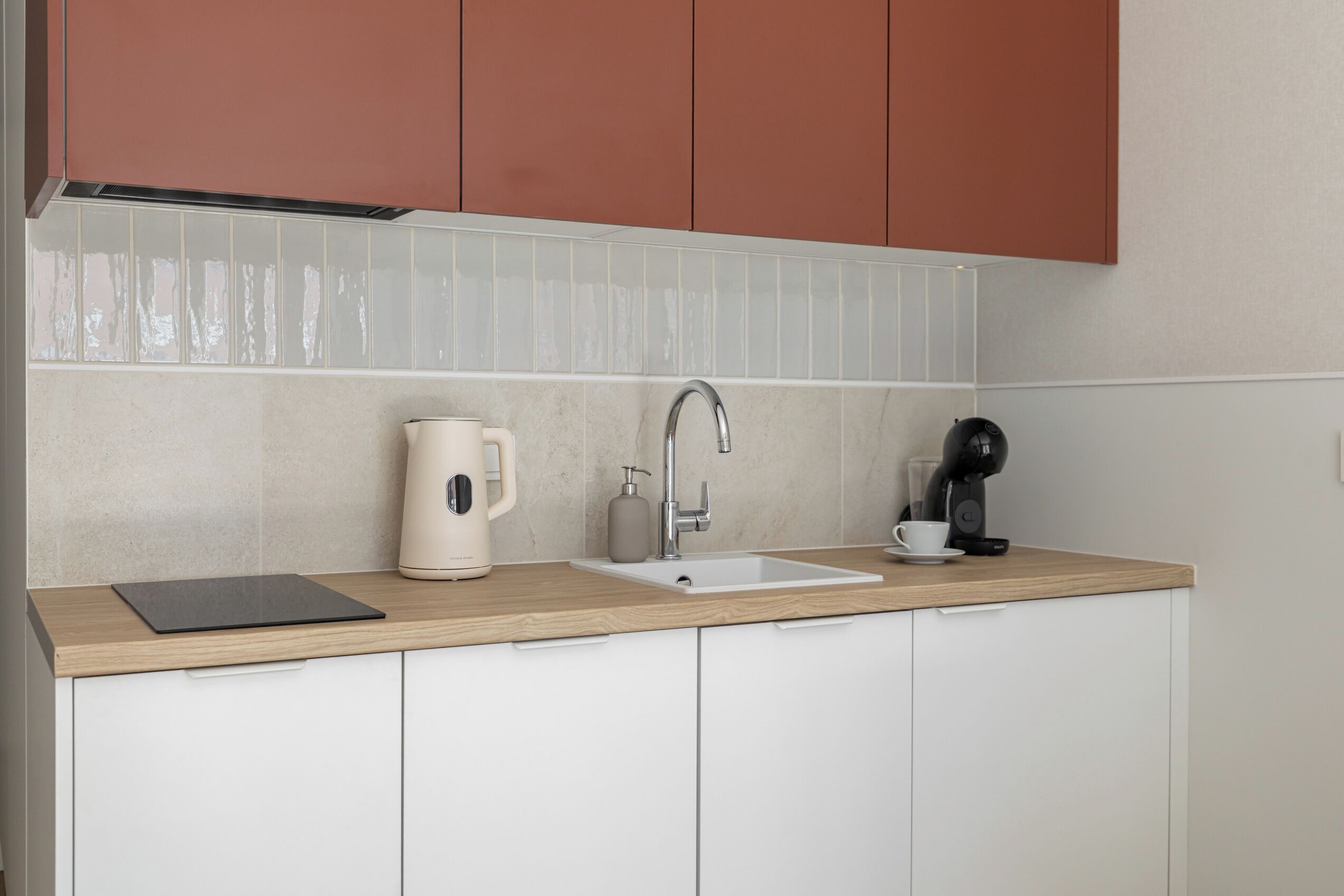 A kitchen with a sink, a coffee maker, and a tablet on the counter.