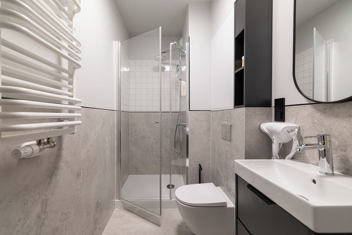 A modern bathroom with a glass shower enclosure, a white sink, and a toilet.