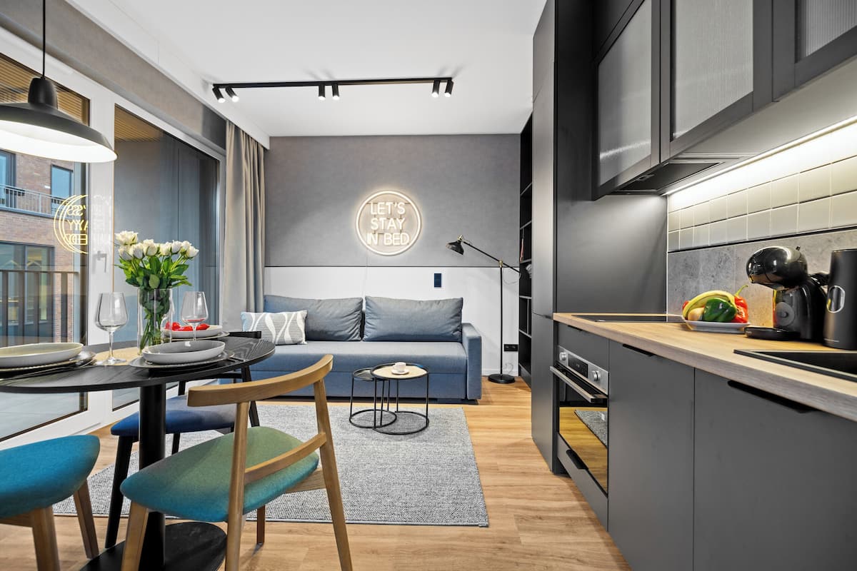 A modern kitchen with a dining area, a sofa, and a neon sign.