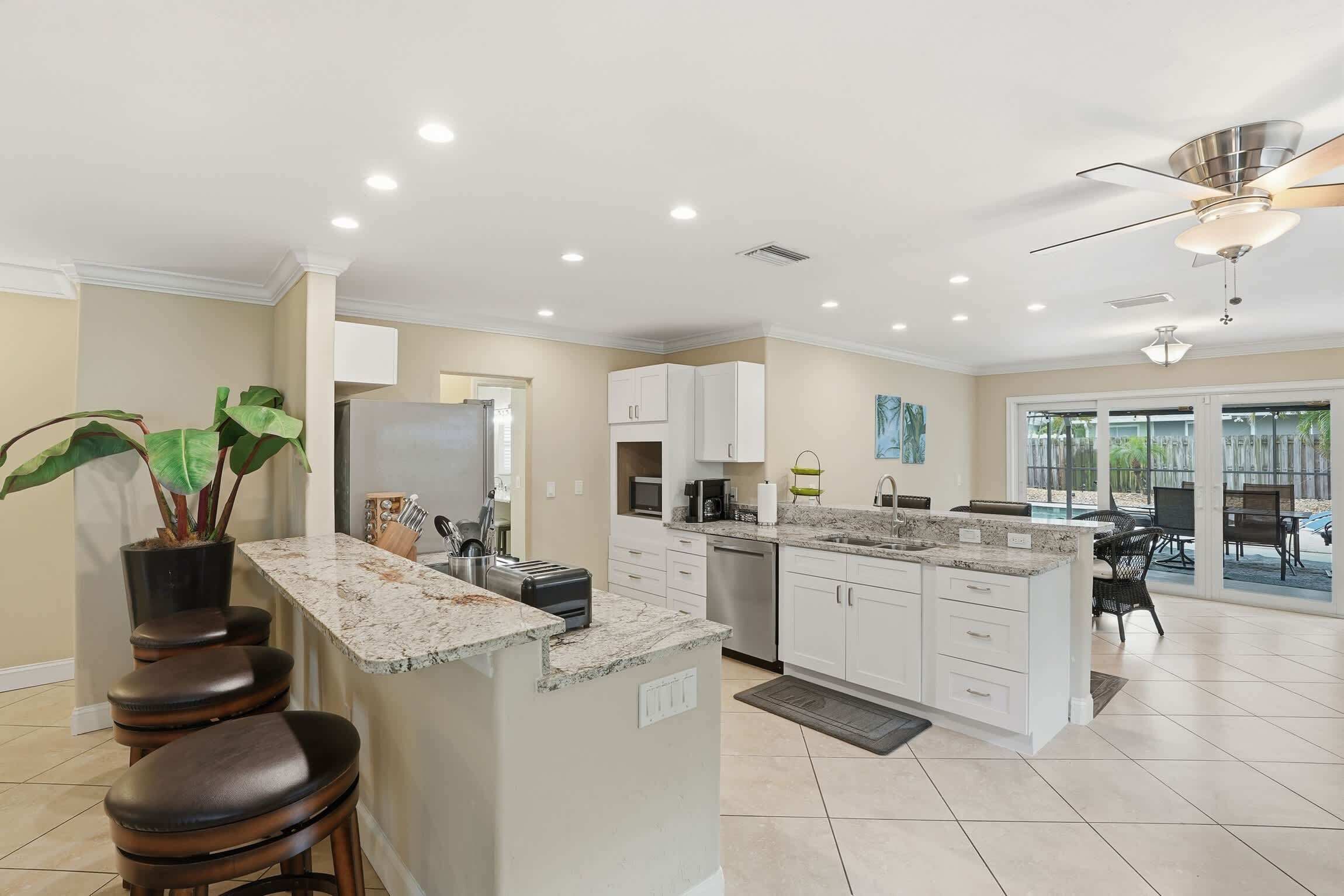 A modern kitchen with a central island, white cabinetry, and a large window providing a view of the outdoors.