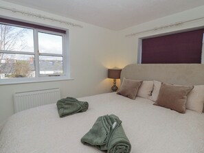 A bedroom with a bed, pillows, a lamp, a window, and a radiator. - Cariad Cottage (Hereford)