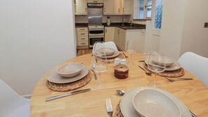 A dining table set for four with plates, glasses, and cutlery. - Cariad Cottage (Hereford)