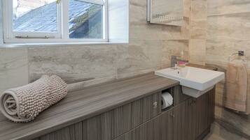 A modern bathroom with a wooden vanity, a white sink, and a towel.