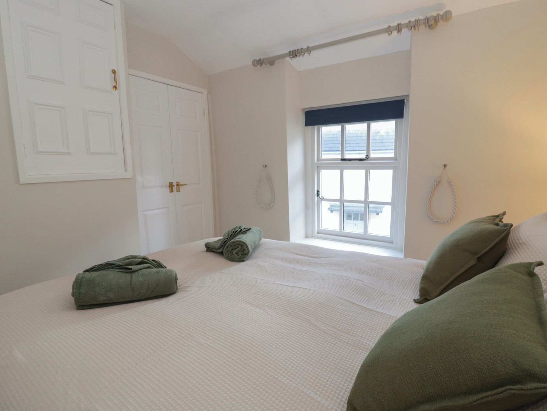 Una camera da letto con un ampio letto, una finestra vista e una porta con maniglia in ottone.
