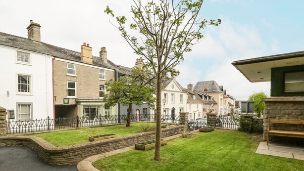 A residential street with houses, a tree, and a stone wall. - Cariad Cottage (Hereford)