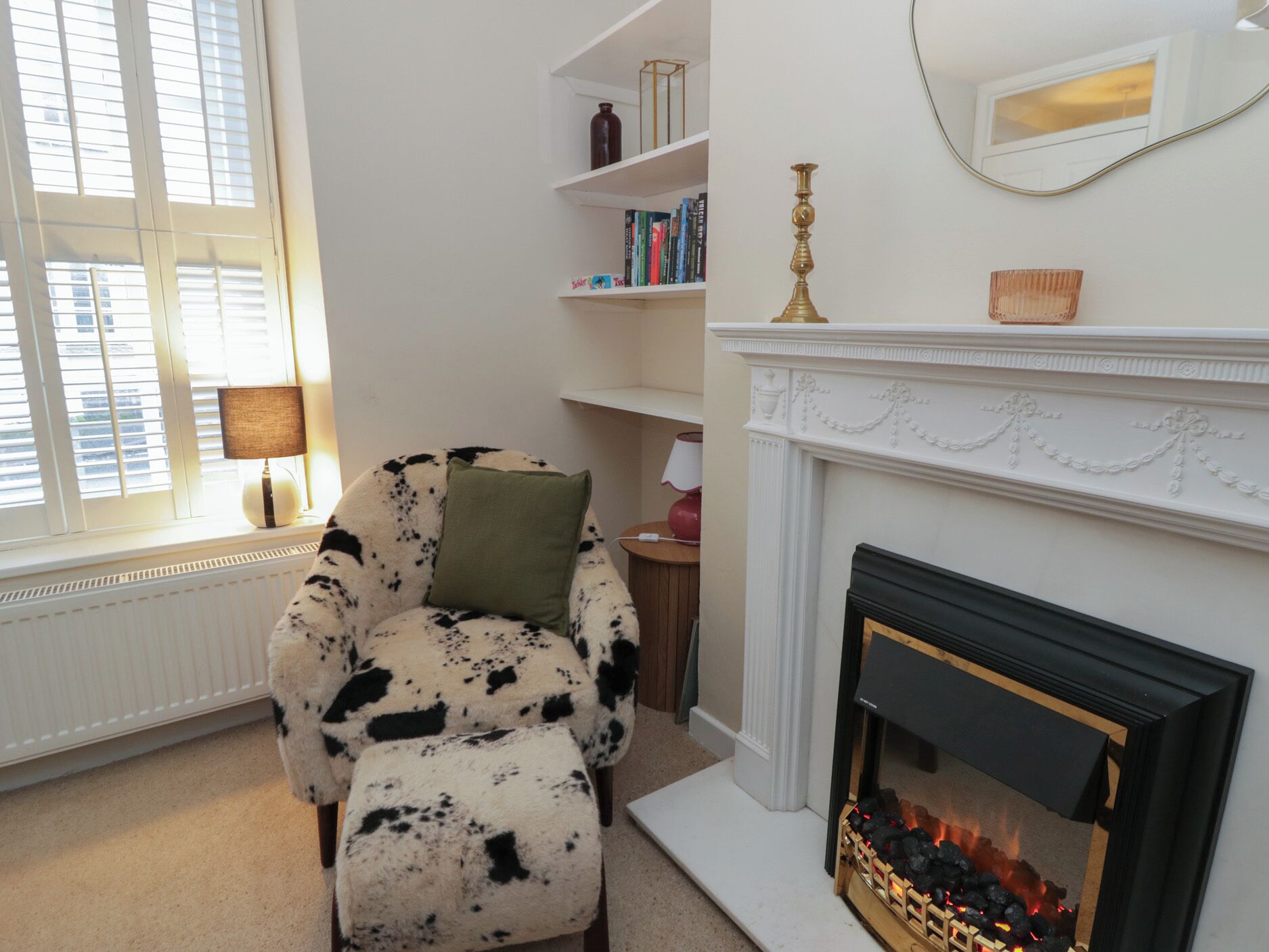 A cozy living room with a fireplace, a comfortable armchair, and a bookshelf.