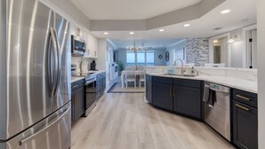 Uma cozinha moderna com eletrodomésticos de aço inoxidável, uma ilha central e vista para a sala de jantar.