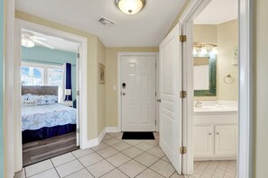 Ein Schlafzimmer mit Bett, ein Badezimmer mit Waschbecken und Spiegel sowie ein Flur mit Tür.