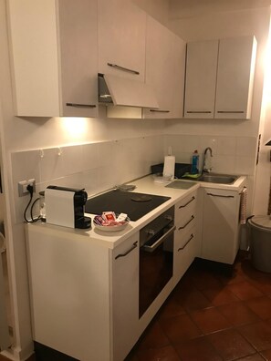 A compact kitchen with white cabinets, a black countertop, a built-in oven, and a sink. - APARTMENT IN THE HISTORIC CENTRE OF FOLIGNO (Foligno)