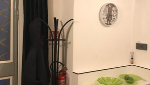 Une pièce avec un meuble blanc, un extincteur et une horloge au mur.