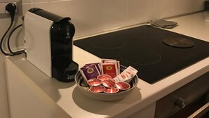 Une cuisine équipée d’une plaque de cuisson à induction noire, d’une bouilloire et d’un bol rempli de sachets de thé, le tout posé sur le comptoir.