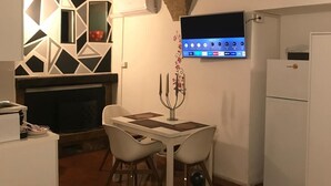 Une cuisine compacte avec un coin repas, un téléviseur fixé au mur et une cheminée.