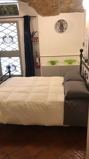 A bed with a white and gray duvet, a green bowl on a bedside table, and a wall clock. - APARTMENT IN THE HISTORIC CENTRE OF FOLIGNO (Foligno)