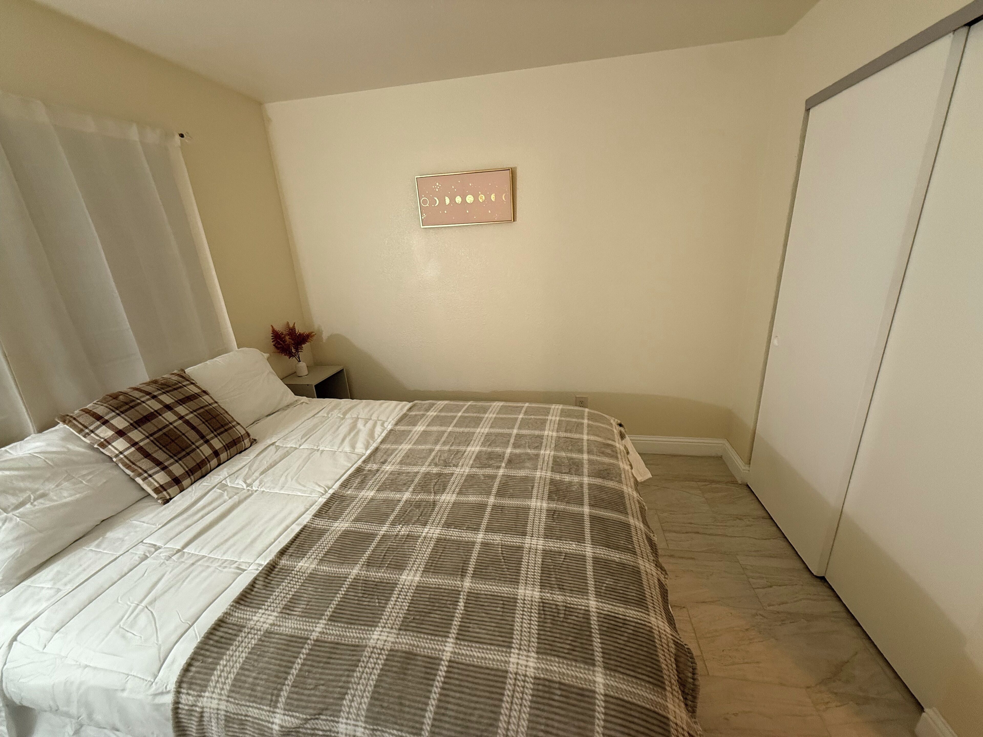 A bedroom with a bed, a nightstand, a wall clock, and a wardrobe.
