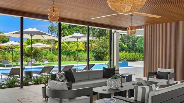 A modern outdoor lounge area with a pool, large umbrellas, and a view of the pool. - 1-Acre Oasis: Pool/Spa, Pickleball, Bball & More (Miami)