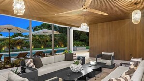 A modern outdoor lounge area with a pool, comfortable seating, and large umbrellas. - 1-Acre Oasis: Pool/Spa, Pickleball, Bball & More (Miami)