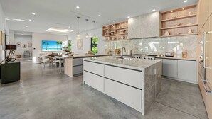 A modern kitchen with a central island, built-in cabinets, and pendant lighting. - 1-Acre Oasis: Pool/Spa, Pickleball, Bball & More (Miami)
