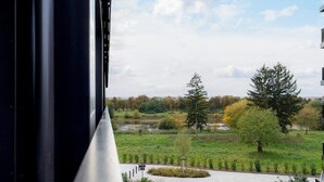 A view from a window overlooking a park with trees and a pathway. - Gleam Homes Marina Garden Dresden (Dresden)