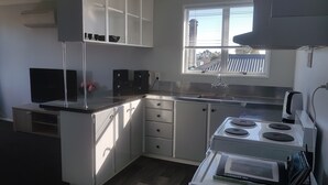 Ett modernt kök med vita skåp, en inbyggd spis och ett fönster med utsikt över omgivningen.