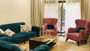 Un salon avec un canapé turquoise, une table basse et deux fauteuils.