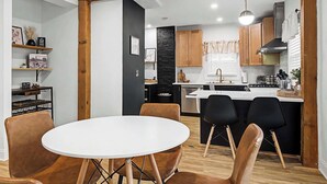 Een moderne keuken met houten kastjes, een centraal eiland en een eethoek met een ronde tafel en stoelen.