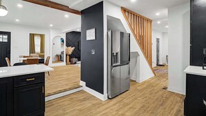 Een moderne keuken met een inbouwkoelkast, houten vloeren en een trap naar een ander niveau.