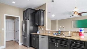 A modern kitchen with dark cabinetry, stainless steel appliances, and a granite countertop. - Beach Haven: 6 Beds, Pet Friendly, 8miles to Beach (Mary Esther)