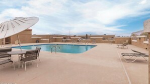 Un espace piscine aménagé sur le toit, avec des chaises longues, une table et des parasols.