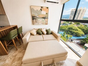 A modern living room with a sofa, chairs, and a painting on the wall. - Apartamentos VITA 219 - by SOHO (Santa Marta)