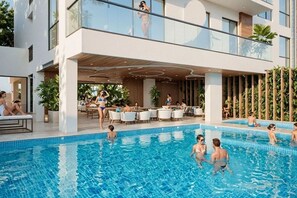 A modern hotel with a pool area, outdoor seating, and a covered patio. - Apartamentos VITA 219 - by SOHO (Santa Marta)