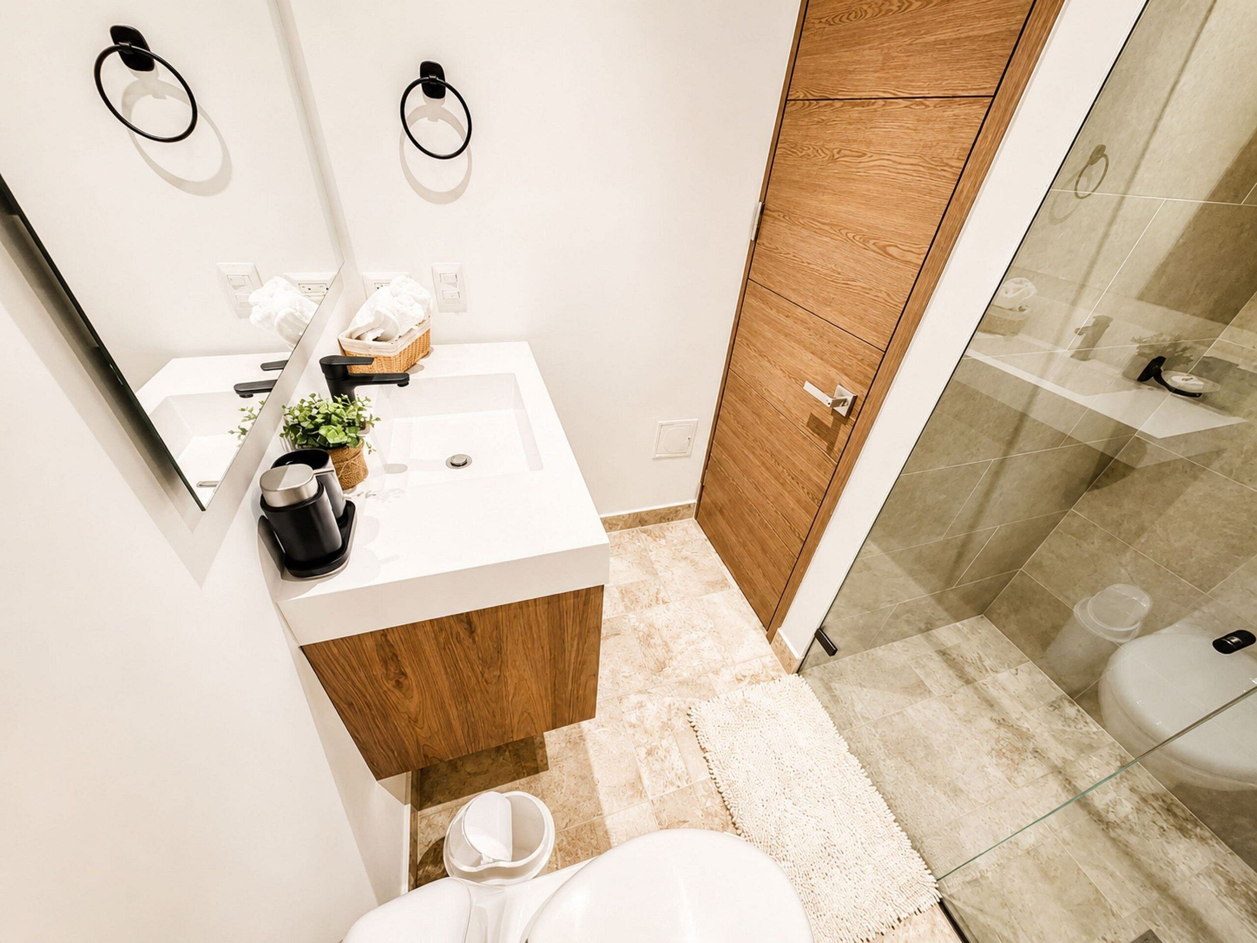 A bathroom with a white sink, wooden cabinet, and a glass shower enclosure.
