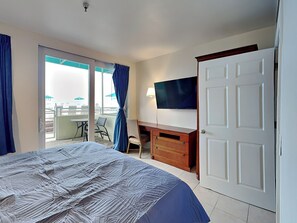 Camera d'albergo con un letto, una scrivania, una sedia, una televisione e una porta scorrevole che dà su un balcone con vista.
