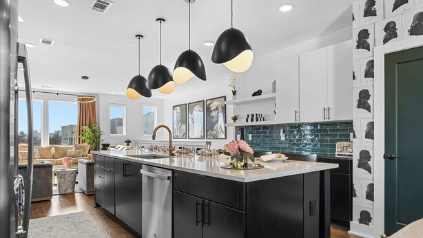 A modern kitchen with black cabinets, a large island, pendant lighting, and a city view. - City Views | Rooftop Deck | Fire Pit + Grill (Nashville)