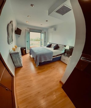 A bedroom with a bed, bedside table, lamp, and a view through a sliding door to the outside. - Red House Rooms (Llucmajor)