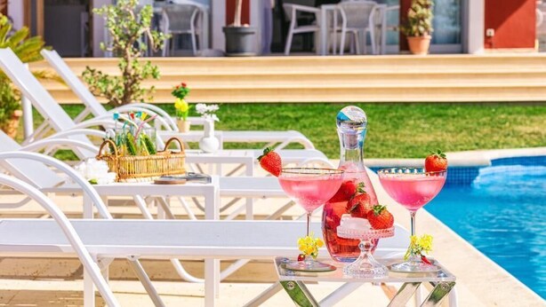 A poolside setting with lounge chairs, a table with drinks, and a clear view of the pool. - Red House Rooms  (Llucmajor)