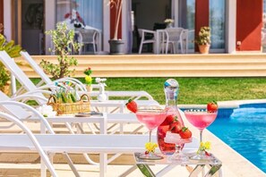 A poolside setting with lounge chairs, a table with drinks, and a clear view of the pool. - Red House Rooms  (Llucmajor)