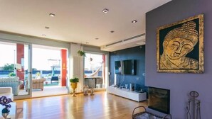 A spacious living room with a large window, a flat-screen TV, and a Buddha painting on the wall. - Red House Rooms  (Llucmajor)
