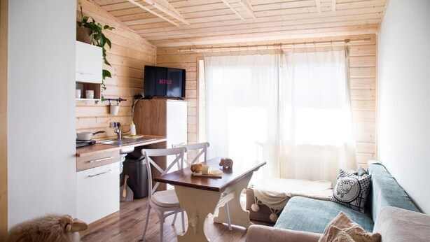 A cozy cabin-style room with a wooden interior, a dining table, a sofa, and a television. - Miedzy Owcami Meee (Czorsztyn)