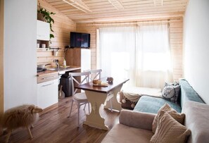 Une pièce confortable, aménagée comme un chalet, avec un intérieur en bois, une table à manger, un canapé et un téléviseur.