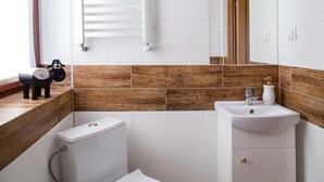 A bathroom with a toilet, sink, and wooden wall tiles. - Miedzy Owcami Meee (Czorsztyn)