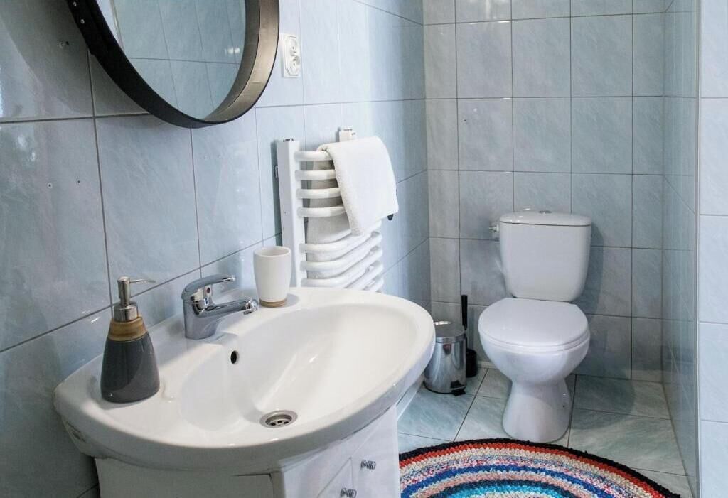 A bathroom with a white sink, a mirror, a toilet, and a towel rack.