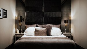 Une chambre à coucher moderne avec un grand lit, deux tables de chevet et une tête de lit sombre.