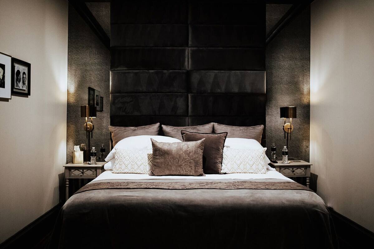 Een moderne slaapkamer met een groot bed, twee nachtkastjes en een donker hoofdbord.
